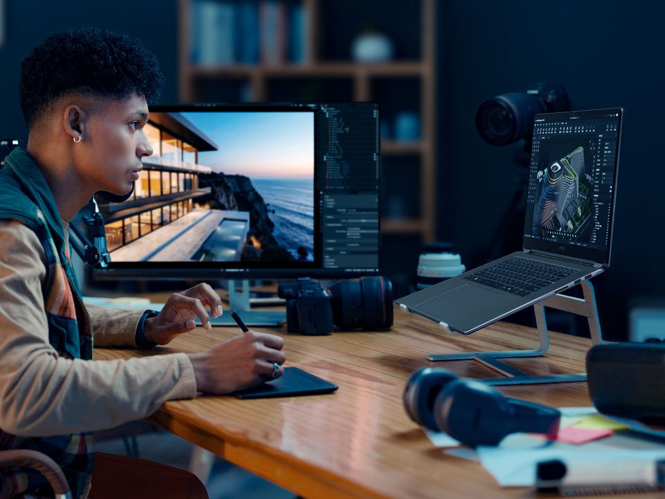 Designer editing on a laptop and a monitor with a camera on the desk